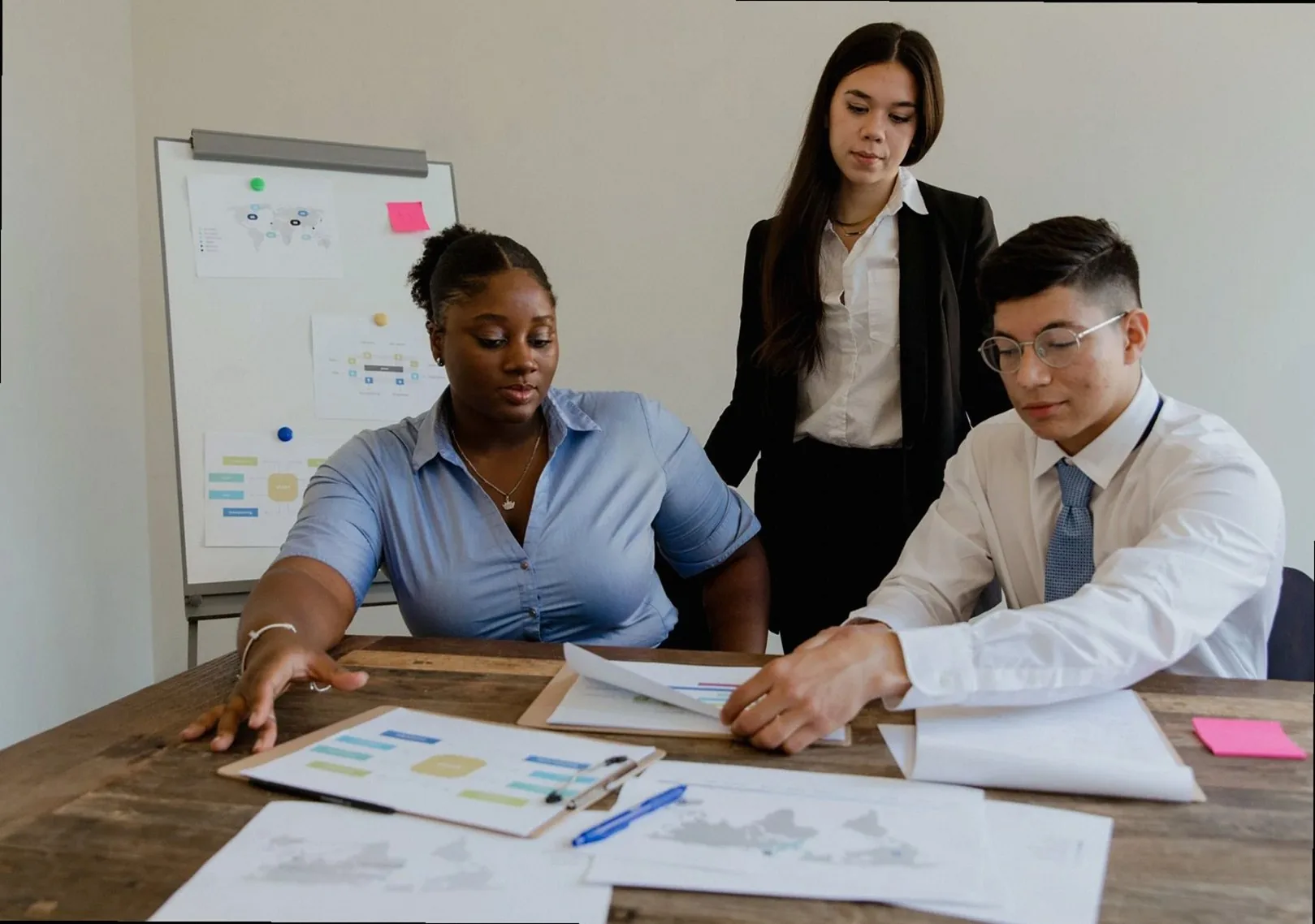 A diverse team discusses business strategies and processes in a modern office space.